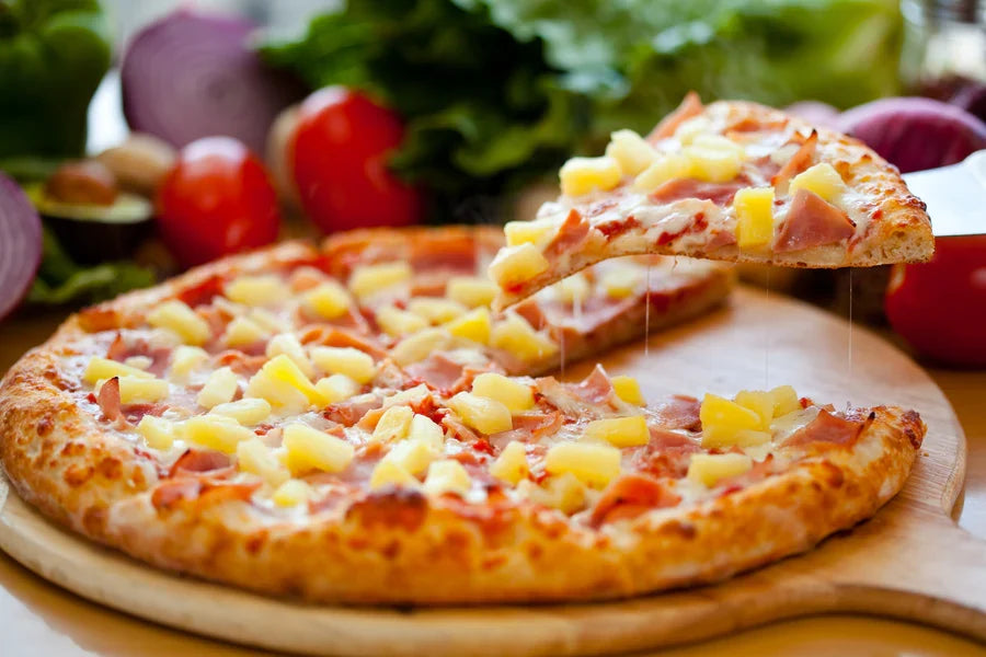 Hawaiian pizza with ham and pineapple on a wooden peel